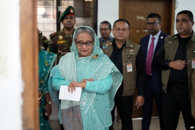 Bangladesh Prime Minister Sheikh Hasina checks her watch as she waits outside a polling station for the official opening time to cast her vote in Dhaka, Bangladesh, Jan. 7, 2024.